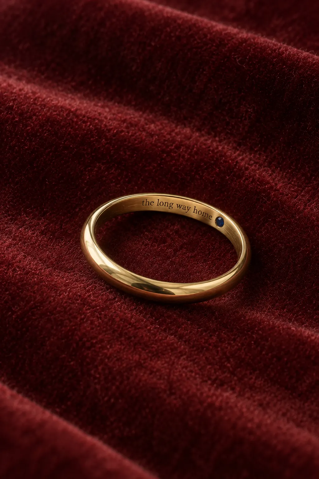 Inside the Ada band on garnet velvet: engraved words and a tiny sapphire.