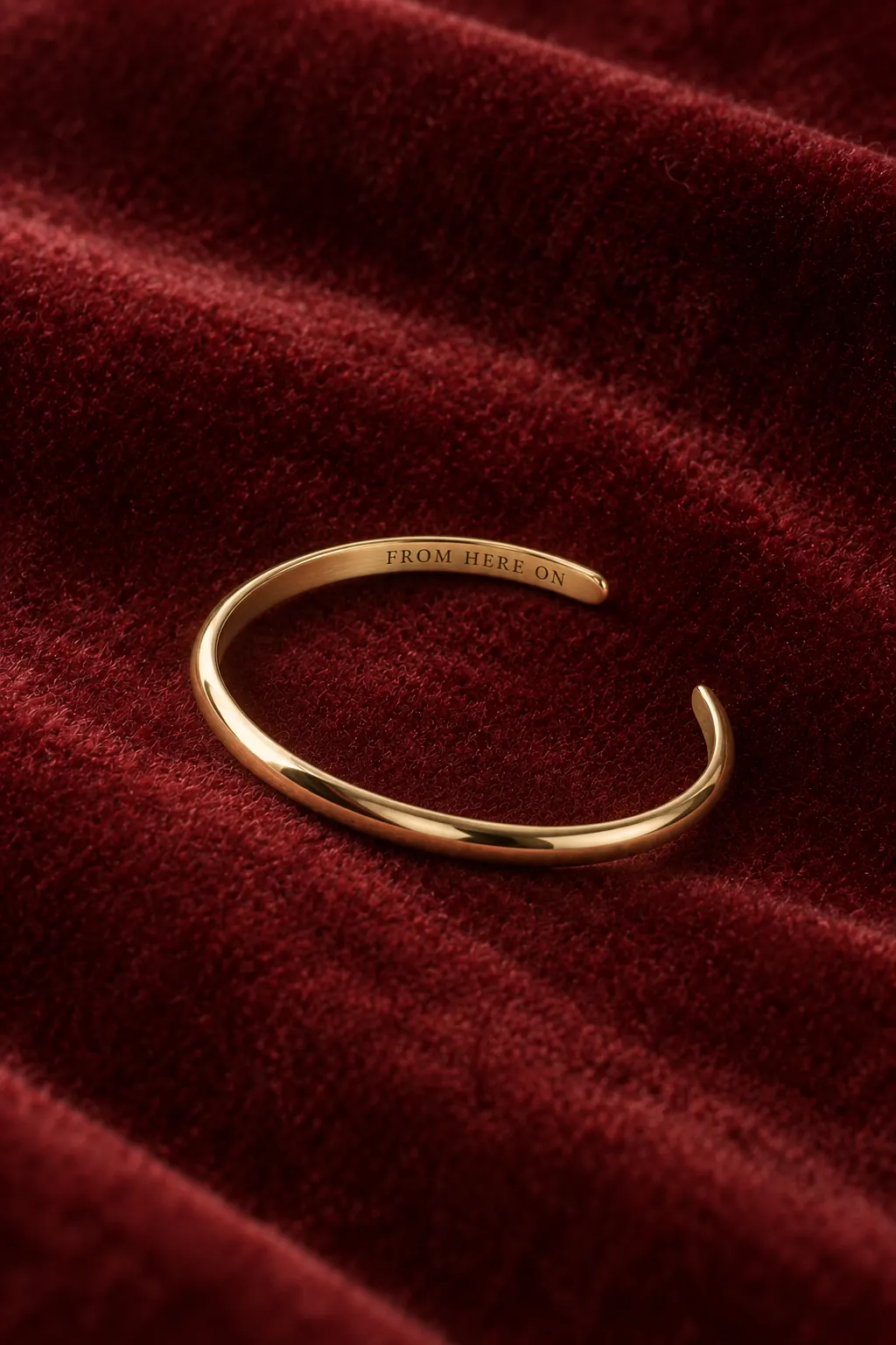 Inside the cuff on garnet velvet: a line of engraved capitals.